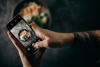Person Holding Black Iphone 5 Taking Photo of Green Leaves