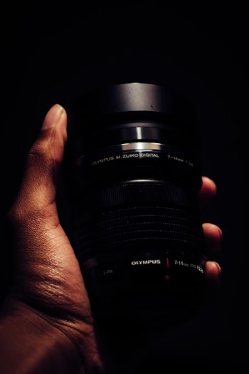 Person Holding Black Olympus Camera Lens