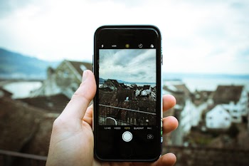Person Holding Black Smartphone Taking a Picture of Brown House at Daytime