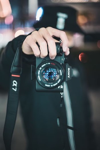 person holding black Sony Alpha DSLR camera