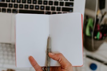 person holding book and black pen