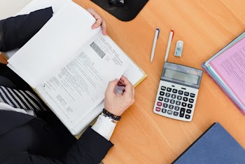 Person Holding Book With Calculator on Table