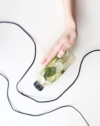 Person Holding Bottle and Cucumber