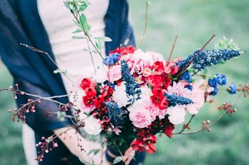 person holding bouquet of pink, red, and blue petaled flowers