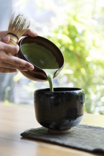 Person Holding Bowl Near Brown Wooden Table
