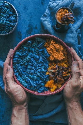 person holding bowl of pasta dish