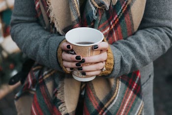 person holding brown and white disposable cup