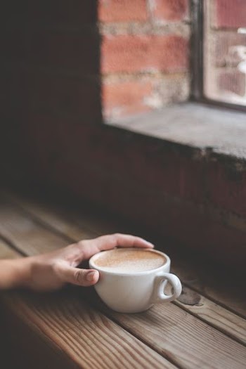 person holding brown ceramic teacup