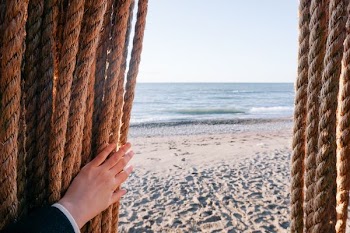 person holding brown rope over seeing body of water