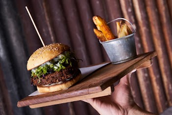 Person Holding Burger on Wooden Tray