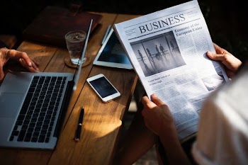 person holding Business newspaper near gray laptop