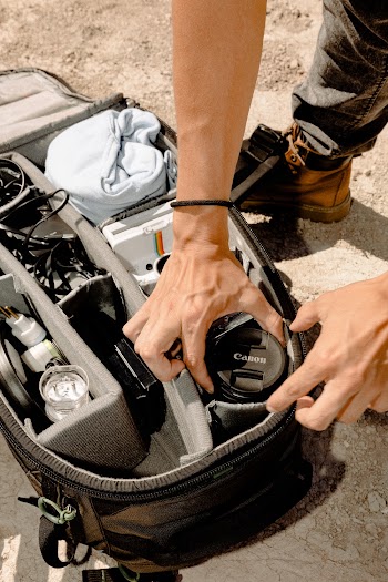 Person Holding Camera Lens in Camera Bag