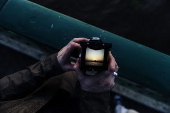 Person Holding Camera With Sunset Display