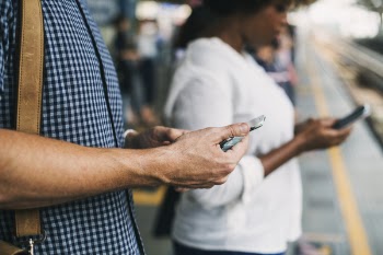 Person Holding Cellphone While Standing on Train Station