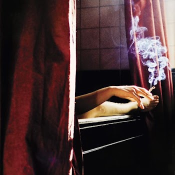 person holding cigarette near window