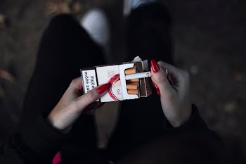 person holding cigarette out of the pack