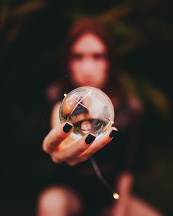 Person Holding Clear Glass Ball Using Right Hand