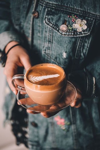 person holding clear teacup on saucer