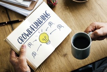 Person Holding Crowdfunding Book and Cup of Coffee