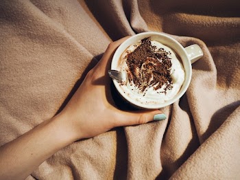 Person Holding Cup With Coffee Latte With Spoon Inside