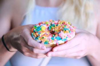 Person Holding Doughnut With Toppings