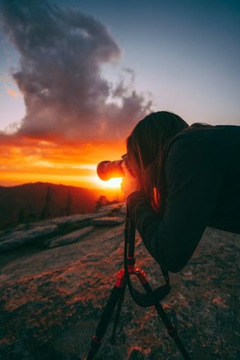 person holding DSLR camera while taking picture