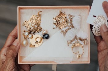 person holding gold-colored earrings in box