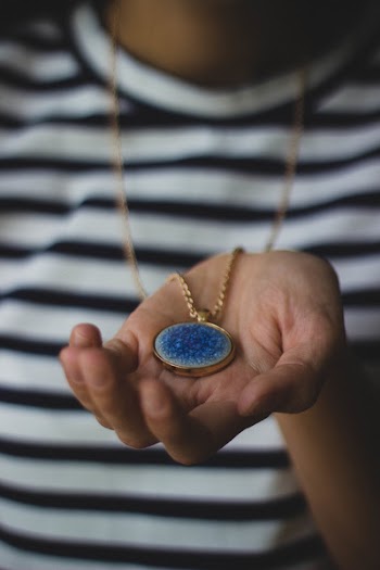 Person Holding Gold-colored Pendant