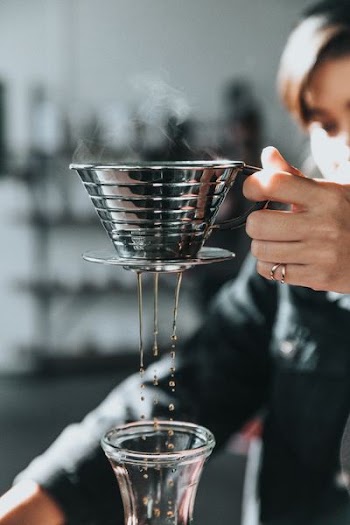 person holding gray stainless steel cup with smoke