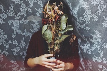 person holding green and red flower bouquet standing against floral background