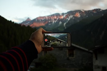 Person Holding Iphone Capturing House and Mountain