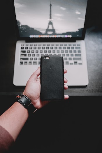 Person Holding Iphone Near Macbook Pro