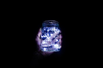 person holding jar with string lights