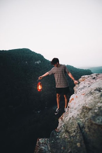 person holding lantern on cliff