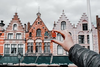 Person Holding Miniature House Toy Comparing on Real Building