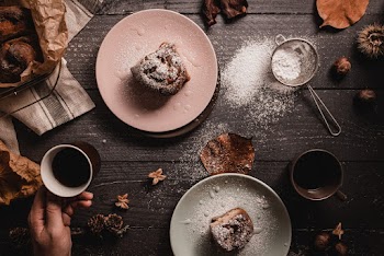 Person Holding Mug Beside Two Plates of Pastry