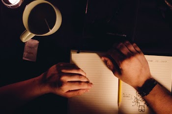 Person Holding Notebook Beside Ceramic Cup
