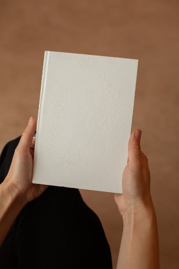 Person holding notebook with blank page in hands
