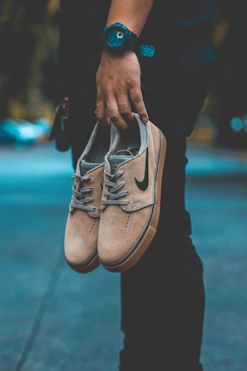 Person Holding Pair of Brown Nike Sneakers