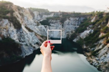 person holding paper facing rock mountain