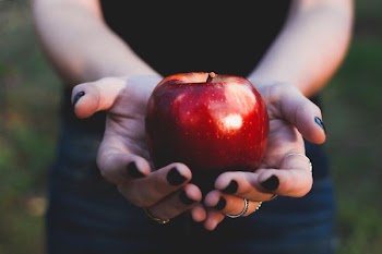 person holding red apple at daytime
