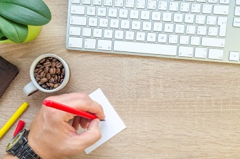Person Holding Red Pen Writing on White Paper