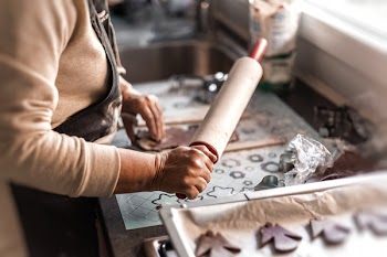 Person Holding Rolling Pin in Front of Flattened Dough Beside Cutted Cookies Inside Kitchen