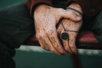 person holding round gold-colored necklace