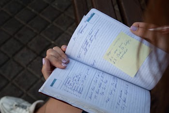 Person Holding Ruled Ntoebook With Yellow Sticky Note