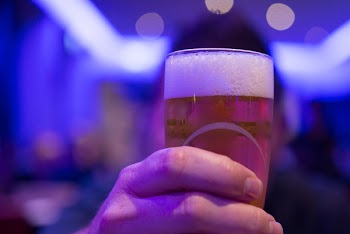 Person Holding Shot Glass Filled With Beer