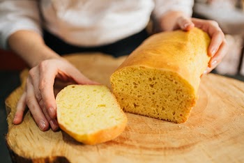 Person Holding Sliced Bread on Brown Wooden Table