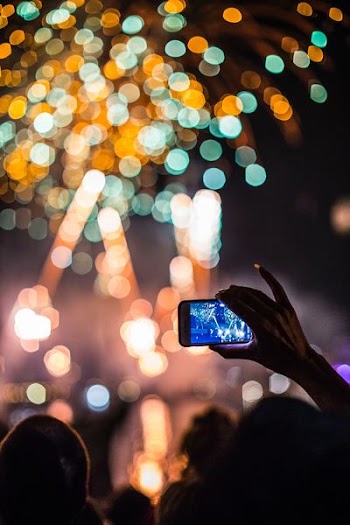 person holding smartphone capturing fireworks