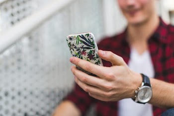Person Holding Smartphone Near White Fence