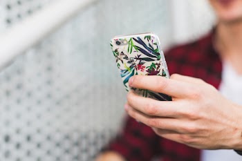 Person Holding Smartphone With White and Green Floral Case
